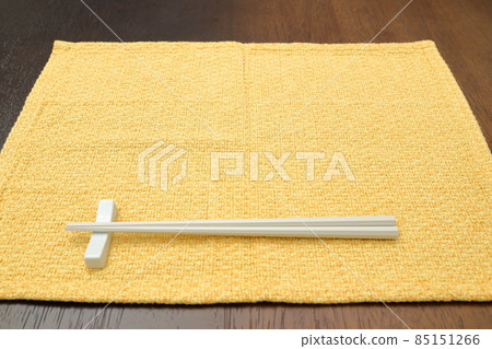 Yellow place mat and white chopsticks 85151266