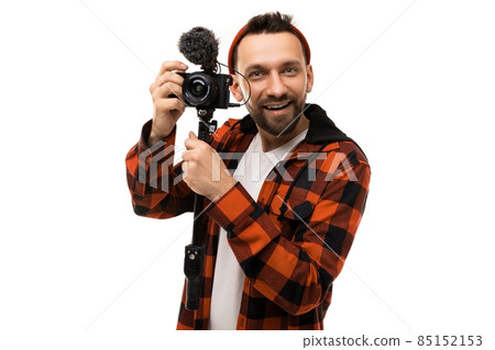 young blogger in a red shirt hat in a black red cage with a video camera on a white background young blogger in a red shirt hat in a black red cage with a video camera on a white background 85152153