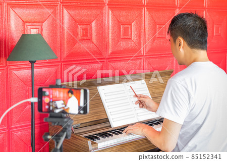 asian music instructor streaming a live video while teaching his student at home. e-learning technology, work from home concept asian music instructor streaming a live video while teaching his student at home. e-learning technology, work from home concept 85152341
