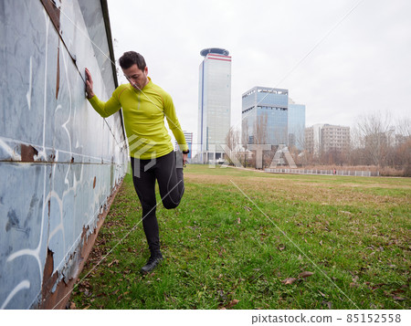 Adult Man running in the parc in winter with city background 85152558
