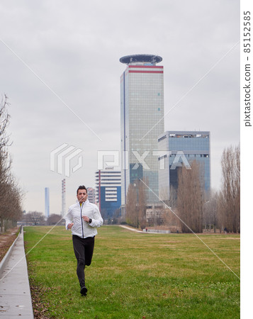 Adult Man running in the parc in winter with city background 85152585