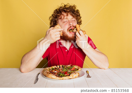 Portrait of red- bearded man tasting delicious Italian pizza isolated on yellow studio background. Portrait of red- bearded man tasting delicious Italian pizza isolated on yellow studio background. 85153568