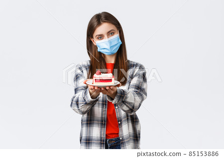 Coronavirus outbreak, lifestyle during social distancing and holidays celebration concept. Tender caring girlfriend made homemade cake, giving it to you, wear medical mask and smiling Coronavirus outbreak, lifestyle during social distancing and holidays celebration concept. Tender caring girlfriend made homemade cake, giving it to you, wear medical mask and smiling 85153886