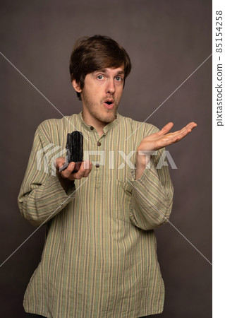 Man holding crystal on grey background 85154258