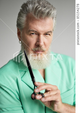 Portrait of brutal middle aged man with beard looking at camera, posing with sharp barber scissors over white background 85154278