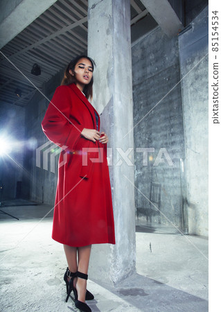 young pretty african american woman in luxury red coat posing fashionable on empty parking building, lifestyle rich people concept 85154534