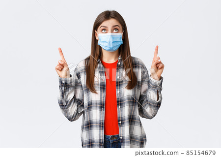 Coronavirus outbreak, leisure on quarantine, social distancing and emotions concept. Surprised and interested cute caucasian girl in casual outfit and medical mask, reading sign upwards, point up Coronavirus outbreak, leisure on quarantine, social distancing and emotions concept. Surprised and interested cute caucasian girl in casual outfit and medical mask, reading sign upwards, point up 85154679