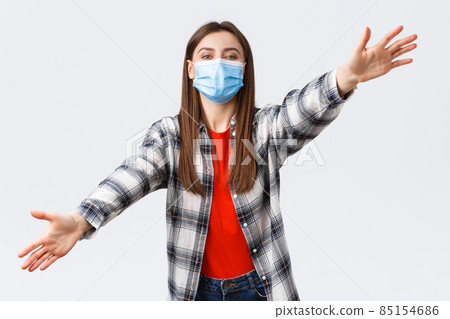 Coronavirus outbreak, leisure on quarantine, social distancing and emotions concept. Cute young woman in medical mask on self-isolation with family, spread hands sideways, dreaming of hugging you Coronavirus outbreak, leisure on quarantine, social distancing and emotions concept. Cute young woman in medical mask on self-isolation with family, spread hands sideways, dreaming of hugging you 85154686
