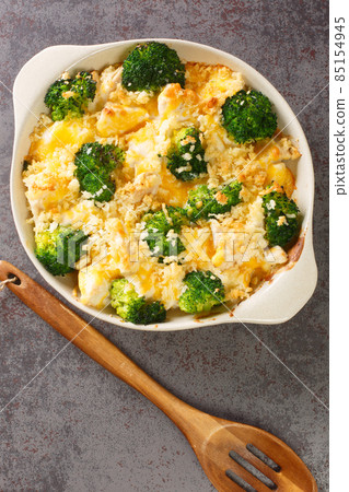 Chicken Divan is a creamy casserole that traditionally made with a chicken, broccoli, cream, cheese close up in the dish. vertical top view Chicken Divan is a creamy casserole that traditionally made with a chicken, broccoli, cream, cheese close up in the dish. vertical top view 85154945