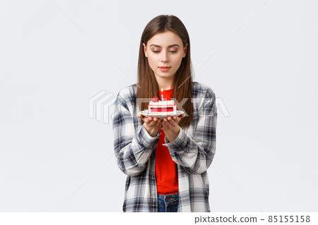 People lifestyle, holidays and celebration, emotions concept. Dreamy attractive birthday girl, woman celebrating b-day, making wish look at lit candle on cake, white background 85155158