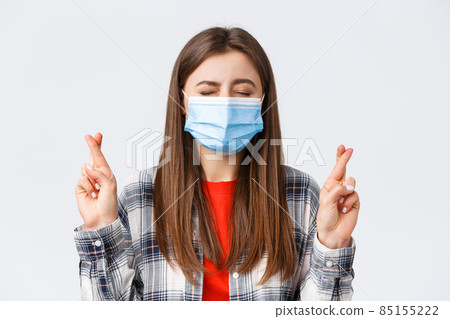 Coronavirus outbreak, leisure on quarantine, social distancing and emotions concept. Close-up of hopeful, dreamy young girl making wish, close eyes and cross fingers good luck 85155222