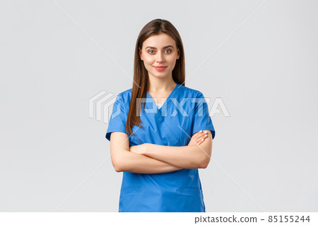 Healthcare workers, prevent virus, insurance and medicine concept. Confident smiling female nurse, doctor in blue scrubs, cross arms chest and look determined. Fighting covid-19 outbreak, stay home 85155244