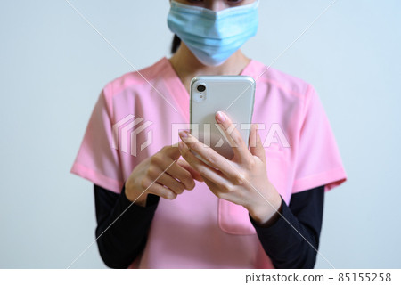 Female healthcare worker wearing a scrub that uses a smartphone Overwork, change of job, turnover, problem solving Female healthcare worker wearing a scrub that uses a smartphone Overwork, change of job, turnover, problem solving 85155258
