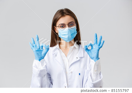Covid-19, preventing virus, health, healthcare workers and quarantine concept. Professional doctor, physician in personal protective equipment, medical mask and gloves, show okay sign, guarantee 85155797