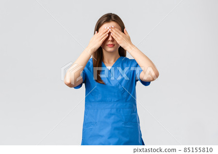 Healthcare workers, prevent virus, insurance and medicine concept. Young woman in blue scrubs, doctor or nurse close eyes with hands, blindfolded medicine, standing grey background Healthcare workers, prevent virus, insurance and medicine concept. Young woman in blue scrubs, doctor or nurse close eyes with hands, blindfolded medicine, standing grey background 85155810