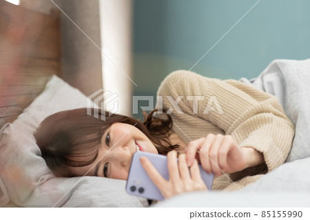 可愛的女人在床上看智能手機 85155990