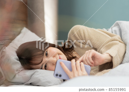 可愛的女人在床上看智能手機 85155991