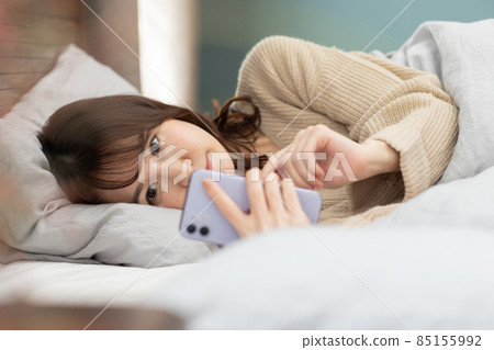 可愛的女人在床上看智能手機 85155992