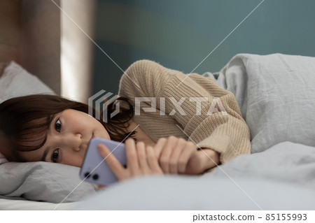 可愛的女人在床上看智能手機 85155993