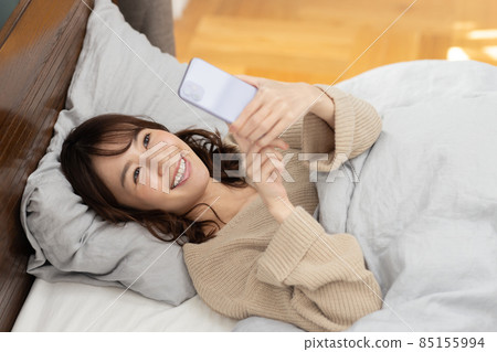 可愛的女人在床上看智能手機 85155994