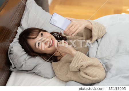 可愛的女人在床上看智能手機 85155995