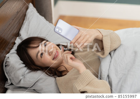 可愛的女人在床上看智能手機 85155997