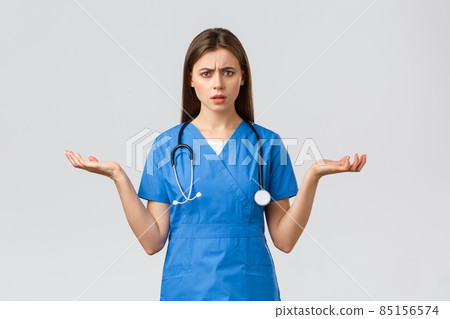 Healthcare workers, prevent virus, insurance and medicine concept. Confused and puzzled female nurse, doctor in blue scrubs, spread hands sideways and shrugging, cant understand 85156574