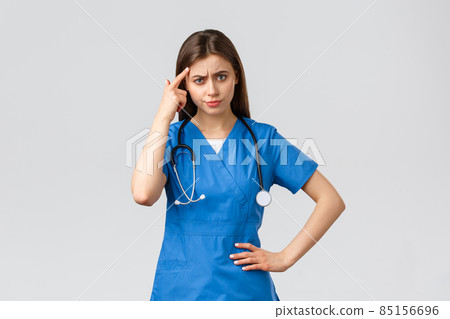 Healthcare workers, prevent virus, insurance and medicine concept. Disappointed angry female nurse, doctor in scrubs pointing at head as scolding patient or coworker, grey background Healthcare workers, prevent virus, insurance and medicine concept. Disappointed angry female nurse, doctor in scrubs pointing at head as scolding patient or coworker, grey background 85156696