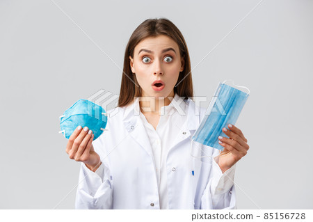 Covid-19, preventing virus, healthcare workers and quarantine concept. Surprised and shocked doctor in white scrubs, gasping and stare astonished, showing medical mask and respirator 85156728