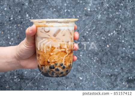 Cropped shot of someone hand holding a cup of iced Bubble milk tea. Bubble tea was a traditional drink in Taiwan before it became hugely popular all over the world. 85157412