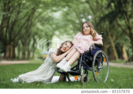 Woman having picnic at park with female friend in wheelchair 85157870