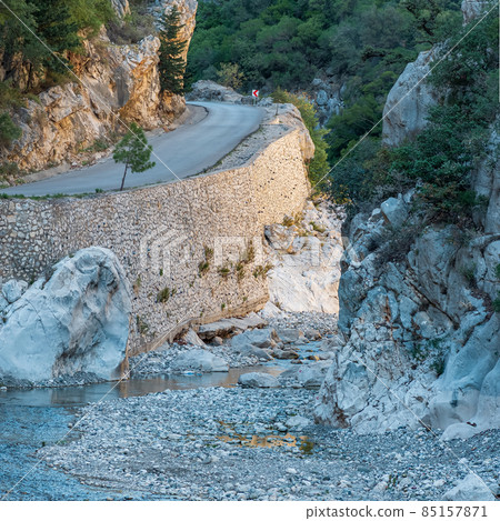 road is laid along the bottom of the mountain gorge with steep limestone slopes road is laid along the bottom of the mountain gorge with steep limestone slopes 85157871