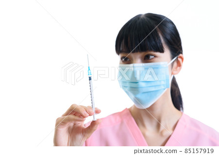 Female healthcare worker wearing a scrub holding a syringe and trying to inoculate a white background, a needle water drop on a focus syringe Female healthcare worker wearing a scrub holding a syringe and trying to inoculate a white background, a needle water drop on a focus syringe 85157919