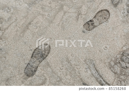 Footprint from the sole of a man's foot shoe against the sand Footprint from the sole of a man's foot shoe against the sand 85158268