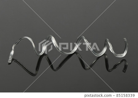 White plastic coated wire tie used for a variety of things on black acrylic background. White plastic coated wire tie used for a variety of things on black acrylic background. 85158339