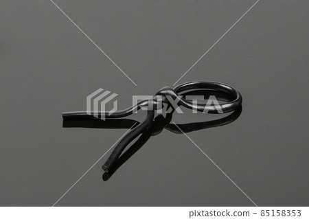 Black plastic coated wire tie used for a variety of things on black acrylic background. 85158353