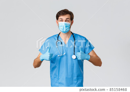 Healthcare workers, coronavirus quarantine campaign and pandemic concept. Cheerful doctor in scrubs, medical mask and protective gloves staying safe fighting covid-19, thumbs-up, recommend clinic 85158468