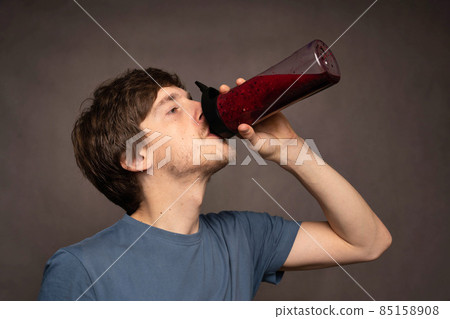 Young man with smoothie on grey background Young man with smoothie on grey background 85158908