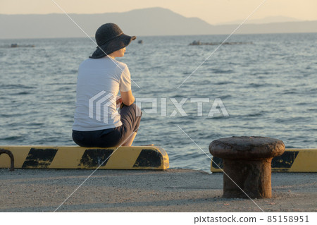 Nostalgic scenery of the back of a woman standing while looking at the sea 85158951