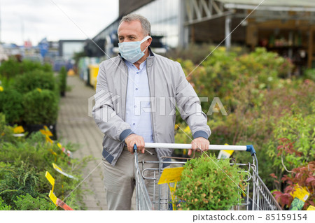 Man in face mask choosing seedlings in market Man in face mask choosing seedlings in market 85159154