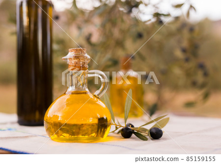 still life of olives and oil on a table against a background of olive trees still life of olives and oil on a table against a background of olive trees 85159155