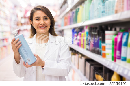 Positive salesgirl helping to choose hair products in cosmetic store Positive salesgirl helping to choose hair products in cosmetic store 85159191