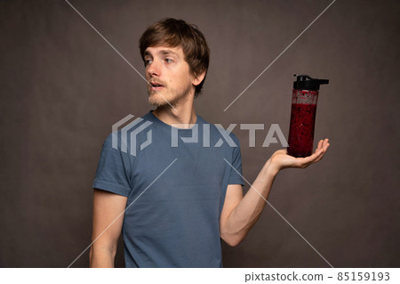 Young man with smoothie on grey background Young man with smoothie on grey background 85159193