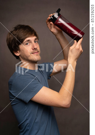 Young man with smoothie on grey background Young man with smoothie on grey background 85159203