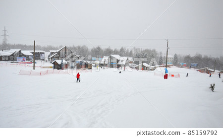 A ski resort in the mountains on Lake Baikal in Eastern Siberia. Snowfall and skiers. A skier in a red jacket on a background of snow . 85159792