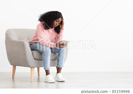 Frustrated black woman looking at smartphone screen Frustrated black woman looking at smartphone screen 85159946