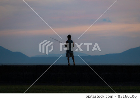 Back view of a boy fishing at dusk Back view of a boy fishing at dusk 85160100