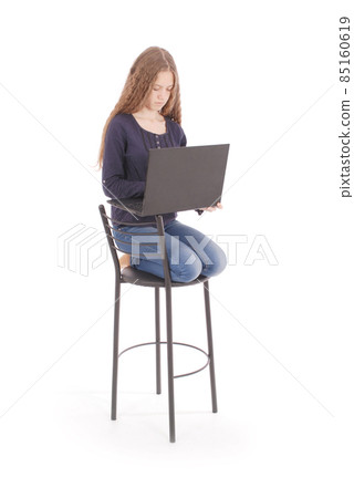 Girl sits on a chair and holding a laptop computer 85160619