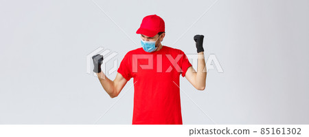 Covid-19, self-quarantine, online shopping and shipping concept. Encouraged and confident delivery man fist pump, feel empowered and happy, fist pump yell yes, accomplish goal, wear face mask 85161302