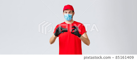 Contactless delivery, payment and online shopping during covid-19, self-quarantine. Friendly courier in red uniform, cap and t-shirt, wear face mask and gloves, thumb-up recommend credit card paying Contactless delivery, payment and online shopping during covid-19, self-quarantine. Friendly courier in red uniform, cap and t-shirt, wear face mask and gloves, thumb-up recommend credit card paying 85161409